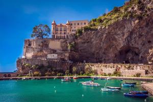 a castle on the side of a mountain with boats in the water at Grecale - stunning sea-view apartment with patio, up to 5 guests in Maiori