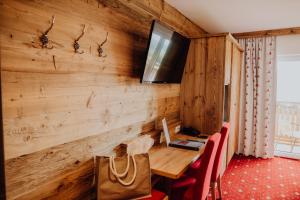 a room with a wooden wall with a table and a television at Panorama Hotel Leidingerhof in Mondsee +59 photos