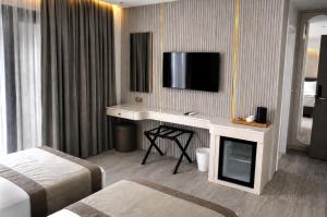 a hotel room with a desk and a tv on the wall at Alpek Hotel Antalya - Lara in Antalya