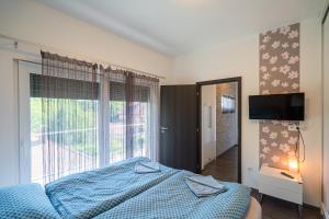 a bedroom with a bed and a large window at AH-Premium Rooftop Apartman in Zamárdi