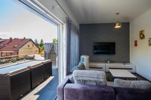 a living room with a couch and a large window at AH-Premium Rooftop Apartman in Zamárdi