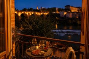 a table with food and wine glasses and a view of a bridge at Au Fil de L eau in Albi