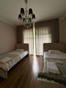 two beds in a bedroom with a chandelier at Карвен коттедж in Bulan Sogottuu
