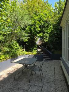 a table and a chair on a patio with trees at Uccle, Pavillon Vert in Brussels