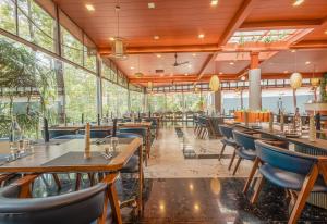 a restaurant with tables and chairs and windows at Mainland Resorts & Spa by Kolaahalam in Yercaud