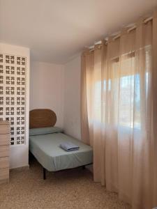 a small bedroom with a bed and a window at Cala Queralt Rooms in Sagunto