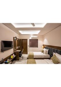 a hotel room with two beds and a flat screen tv at Hotel Raaj Palace in Agra