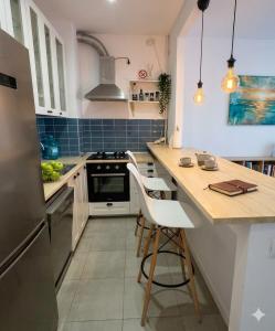 a kitchen with white cabinets and a counter with chairs at MAYA Studio-Onix Blue with Private Parking, Mamaia Nord in Mamaia Sat/Năvodari