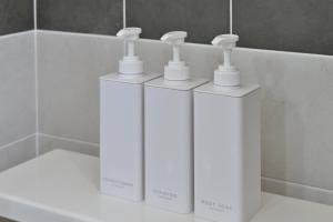 four white bottles sitting on a counter in a bathroom at Shion 潮音 in Sakaide +50 photos