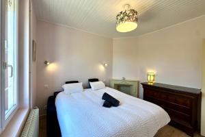 a bedroom with a large white bed with a hat on it at Maison avec jardin entre St-Valery et Le Crotoy in Noyelles-sur-Mer