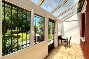 a conservatory with a glass roof with a table and a desk at Maison avec jardin entre St-Valery et Le Crotoy in Noyelles-sur-Mer