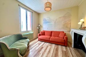 a living room with a red couch and a fireplace at Maison avec jardin entre St-Valery et Le Crotoy in Noyelles-sur-Mer