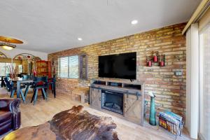 a living room with a fireplace and a tv on a brick wall at Tranquil Trail #8 in Carefree