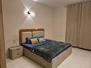 a bedroom with a bed with blue sheets and a window at The Palm Villa in Jaipur