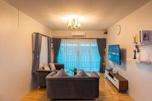 a living room with two couches in front of a window at The Comfy House Prachuap in Sathani Rot Fai