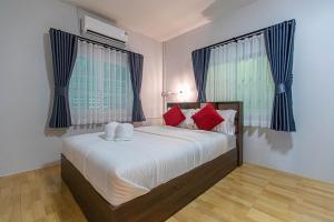 a bedroom with a large white bed with red pillows at The Comfy House Prachuap in Sathani Rot Fai