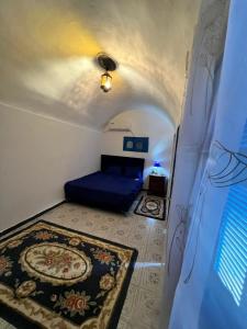 a small room with a blue bed and a rug at Maison vue mer in Rafrāf