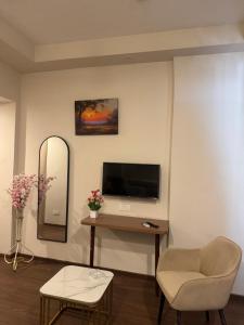 a living room with a tv and a chair and a mirror at the Aurelia estate studio apartment Alpha 2 in Greater Noida
