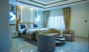 a hotel room with a bed and two chairs at Ocean Front Hotels Enugu in Awkuzu