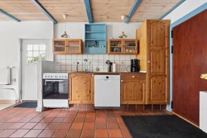 a kitchen with wooden cabinets and white appliances at Charming 45 M House In Peaceful Setting in Gelsted