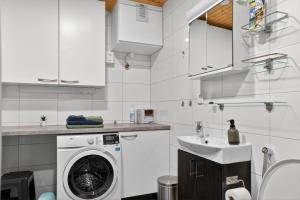 a white kitchen with a washing machine and a sink at Cozy two-room apartment with sauna in Sodankylä