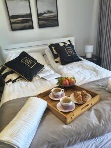 a tray with cups of coffee and pastries on a bed at Mazury Glam Studio in Giżycko