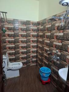 a bathroom with a brick wall and a toilet and a sink at Hotel AAA And Restaurant in Gupta Kāshi