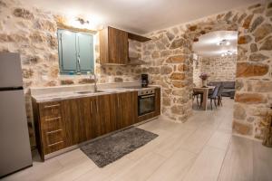 a kitchen with stone walls and a sink and a refrigerator at Mainotti's house in Areopoli