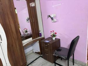 a bathroom with a pink wall with a chair and a vanity at Lara Homestay duplex 3bhk in Secunderabad