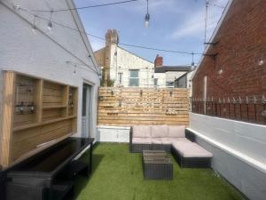 a patio with a couch and a wooden fence at Modern Pink Cottage in Blackpool in Blackpool
