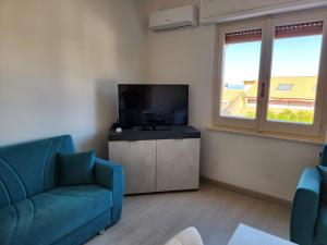 a living room with a blue couch and a flat screen tv at Casa MedeFaby Due in S'archittu Cuglieri