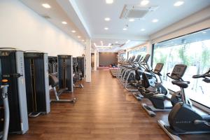 un gimnasio con filas de cintas de correr y elípticas en Socool Grand Hotel, en Nang Rong