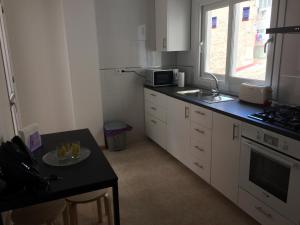 kuchnia z białymi szafkami i czarnym blatem w obiekcie Apartamento Mateos w Murcji