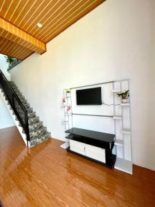 a living room with a tv and a staircase at Kaffana Cabin House in Banjarnegara