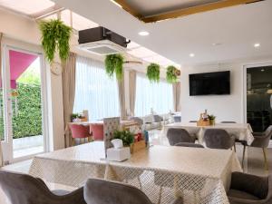 a dining room with tables and chairs and a tv at Christella Hotel Laemchabang in Si Racha