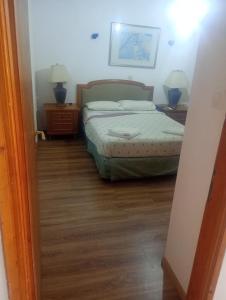 a bedroom with a bed and two night stands and two lamps at Rallis village in Akrata