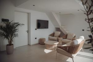 a living room with a couch and chairs and a tv at IONEO Dhermi in Dhërmi