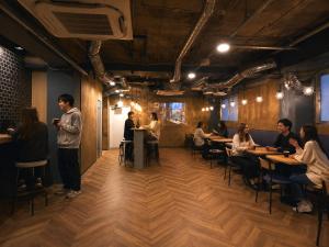 a group of people sitting at tables in a restaurant at Shijo Guesthouse HIVE in Kyoto