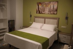 a bedroom with a white bed with a green blanket at Hostal el Ciervo in Burunchel
