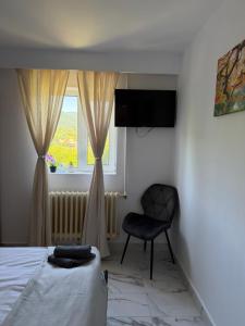 a bedroom with a bed and a chair and a window at Casa NIB Calimanesti in Călimăneşti