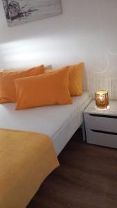 a white bed with orange pillows and a night stand at ApartmaniNET in Krašići