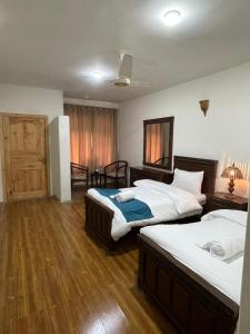 a bedroom with two beds and a wooden floor at Sost Embassy Hotel By Zeez in Khudābād