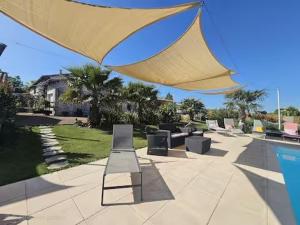 a large yellow umbrella over a pool with a bench at Gite du Passignac in Saint-Maigrin