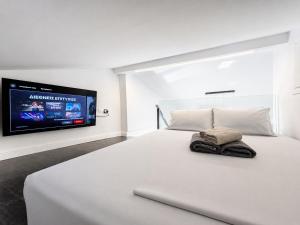 a bedroom with a white bed with a tv on the wall at L'aTTIQUE in Kastanéa +8 photos