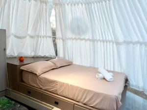 a bed in a bedroom with a window with white curtains at Under the Stars Domes in Shkodër