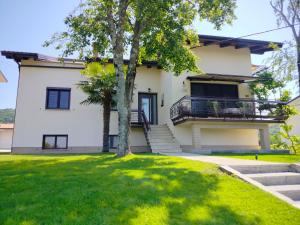 a large white house with a tree in the yard at Apartma Breza in Kojsko +4 photos