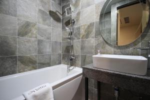 a bathroom with a sink and a tub and a mirror at Busan Station Dino Hotel in Busan