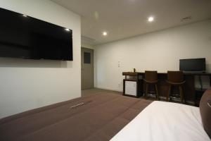 a bedroom with a large flat screen tv on a wall at Busan Station Dino Hotel in Busan