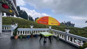 a table with an umbrella on a balcony at Rangdu Homestay in Darjeeling