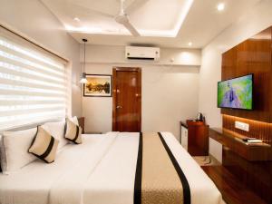 a bedroom with a large bed and a tv at Evara-Meraki Inn in Kolkata